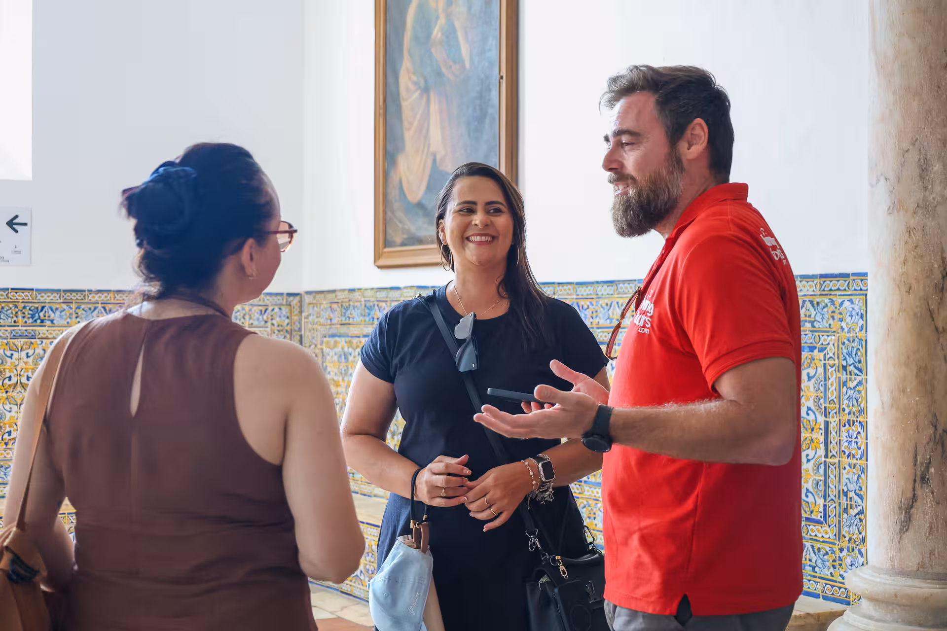 Tour guide engaging with visitors in a beautifully tiled room in Évora, highlighting cultural insights of the tour.