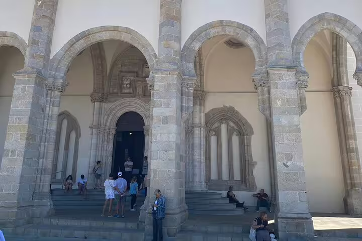 Visitors exploring the grand arches of a historic building on a private tour to Évora from Lisbon.