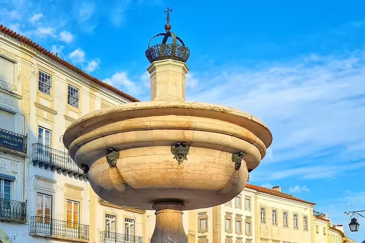 Historic marble fountain in Évora's central square under a bright blue sky, featured on the Évora Essentials tour from Lisbon.