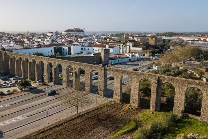 Aerial view of the ancient aqueduct in Évora, Portugal, showcasing its impressive arches and historical architecture on a sunny day.