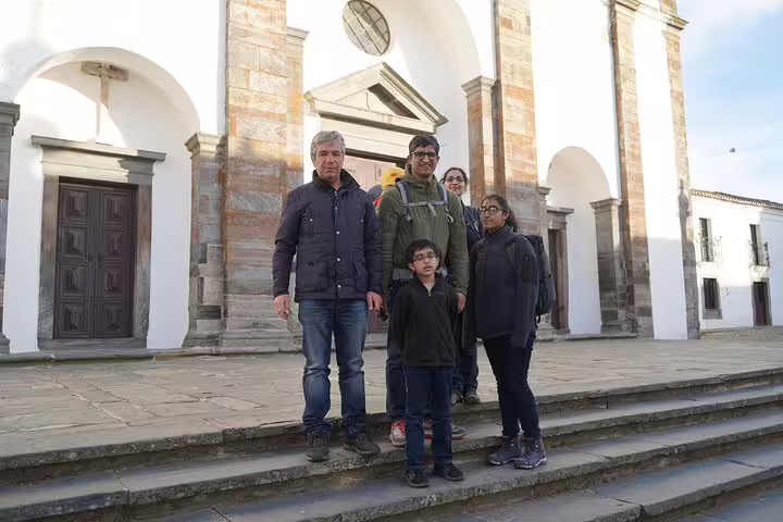 A group of tourists stands on the steps of a historic church in Évora during a day trip from Lisbon, enjoying cultural exploration.