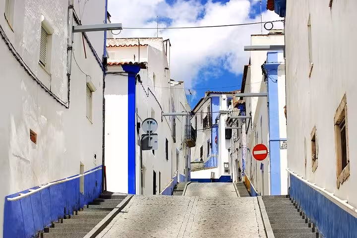 Charming narrow street in Évora with traditional white and blue houses under a clear blue sky.