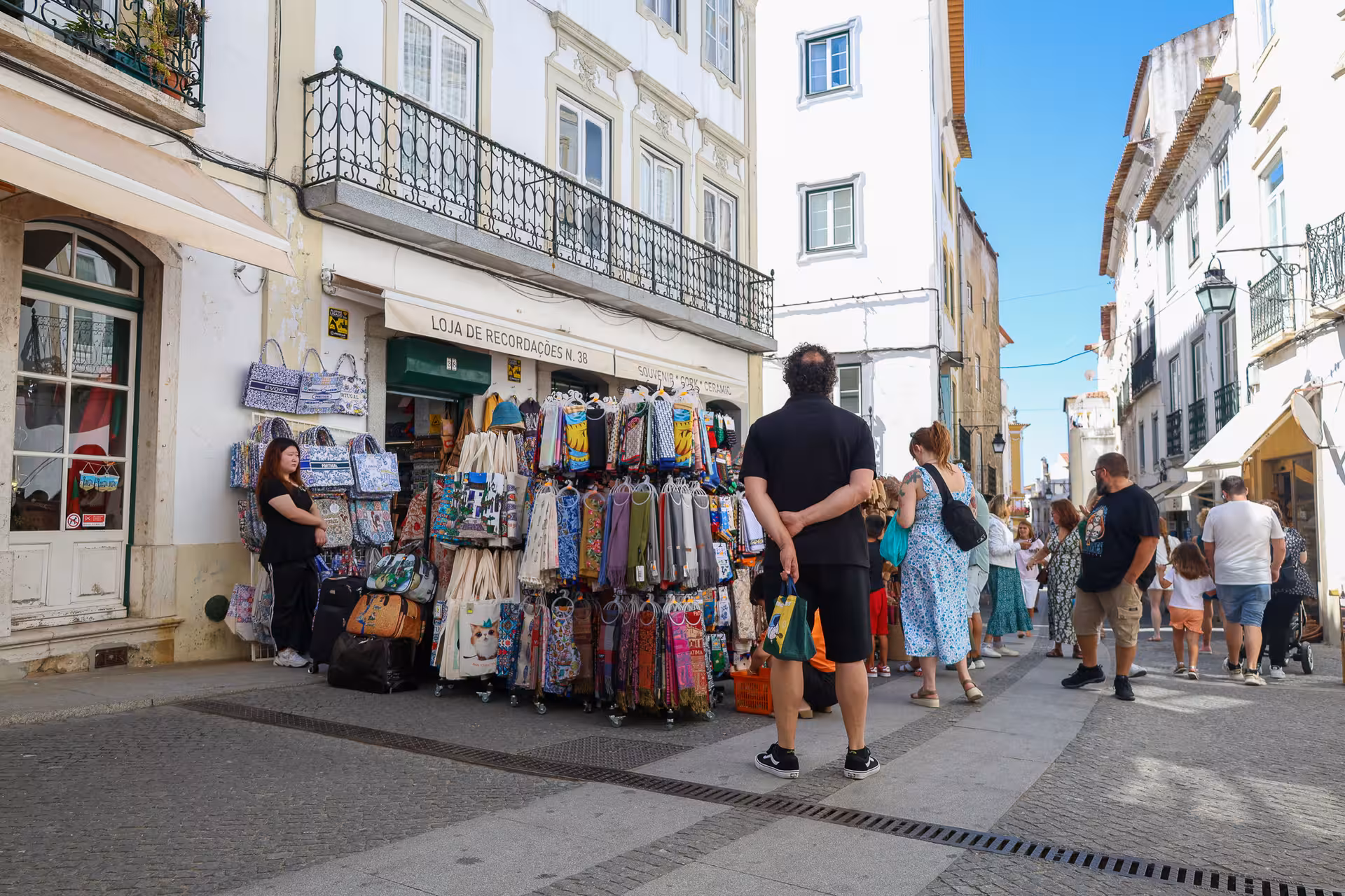 Tourists exploring a bustling souvenir shop in the historic streets of Évora, Portugal.