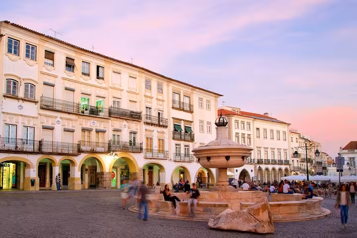 Scenic view of Évora's charming Praça do Giraldo at sunset with historic architecture and lively atmosphere.