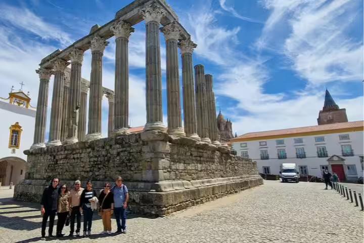 Visitors explore the ancient Roman Temple of Évora on a sunny day, a highlight of the day trip from Lisbon to Évora and Monsaraz.