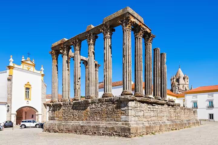 Historic Roman Temple of Évora with grand columns against a vibrant blue sky, a highlight of the private tour.