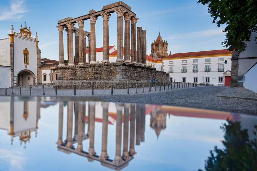 Daytime reflection of Évora’s Roman Temple in a puddle, highlighting historic landmarks on the Lisbon tour.