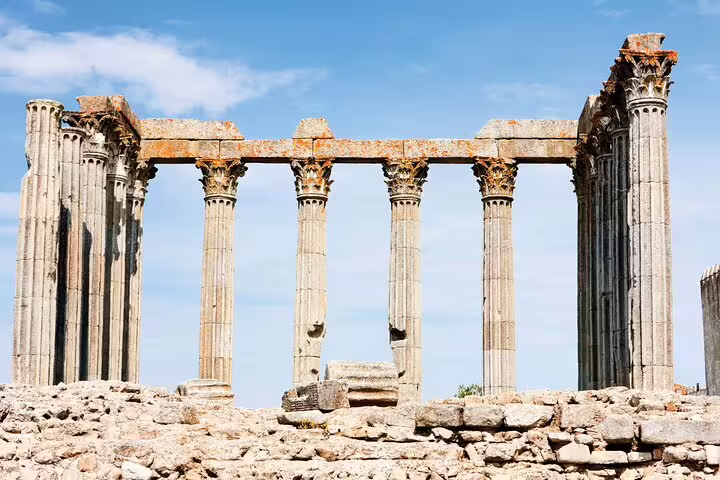 Ancient Roman Temple ruins in Évora, Portugal, featuring Corinthian columns under a clear blue sky, part of a private full-day tour from Lisbon.