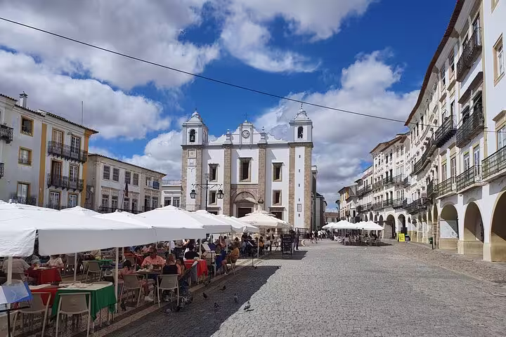 Charming Evora town square with outdoor cafes, historic architecture, and blue skies on a private full-day tour from Lisbon.