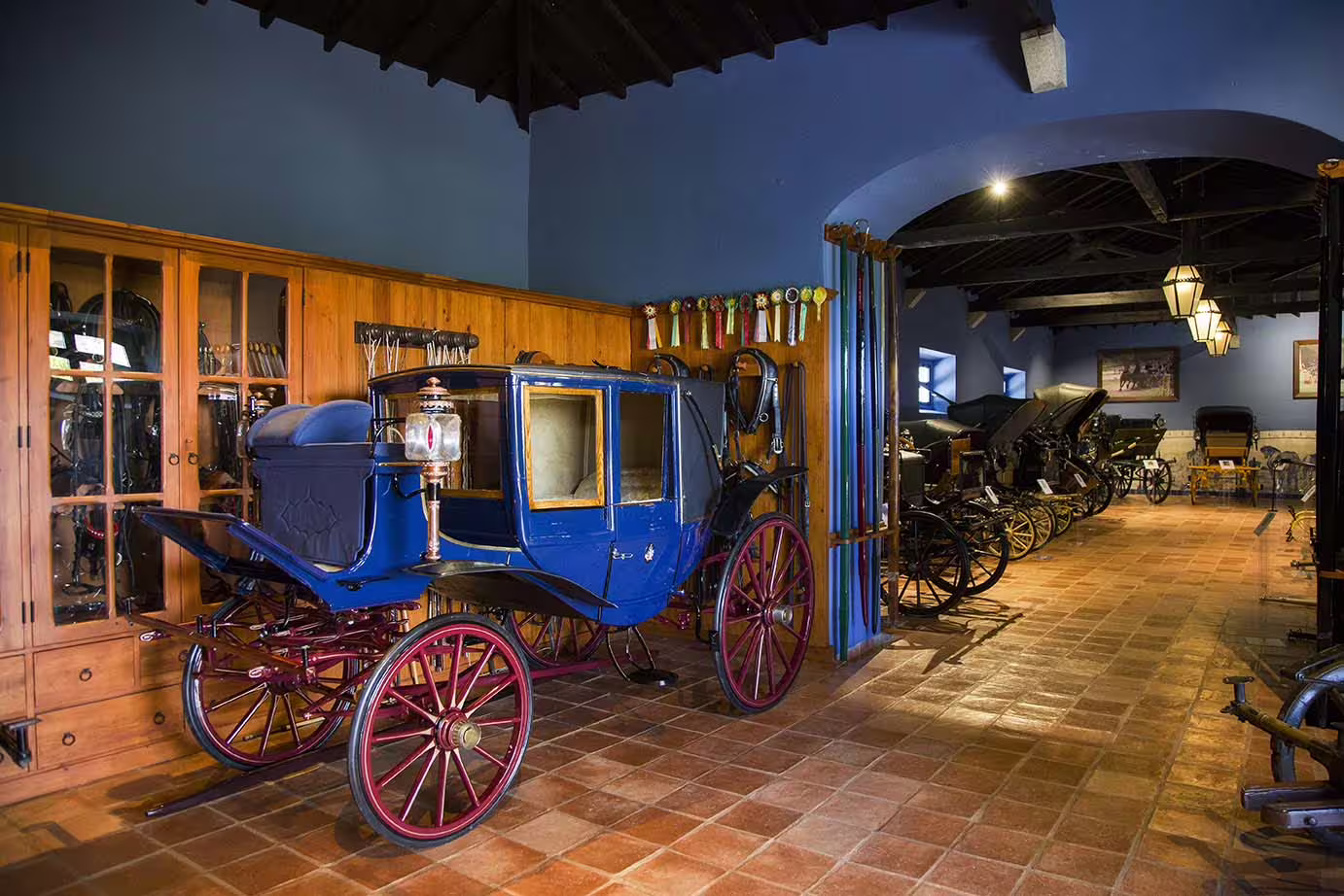 Explore a vintage carriage museum in Évora, featuring a classic blue carriage amidst historic decor and artifacts.