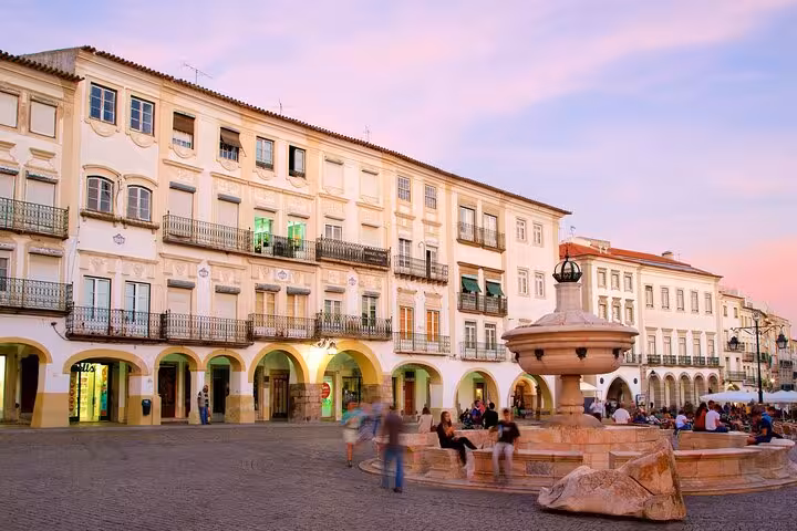Vibrant town square scene at dusk in Évora, showcasing beautiful architecture and a lively ambiance on the walking tour.