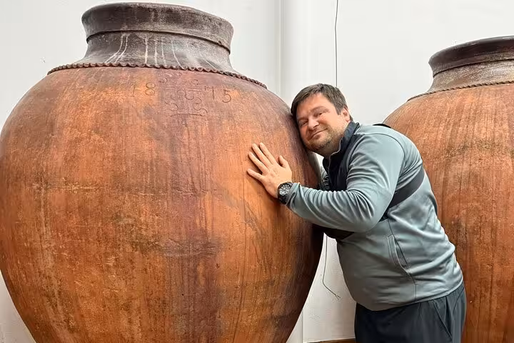 Visitor embracing a large traditional clay wine jar in Évora's cultural wine experience.