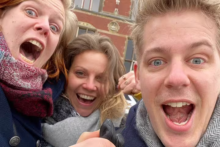 Excited group selfie in Antwerp on a smartphone e-scavenger hunt, solving clues on a self-paced city tour