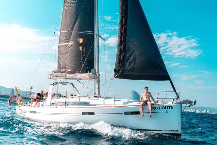 Luxurious sailing yacht gliding through the ocean with guests enjoying a 3-hour exclusive tour featuring tapas and drinks.