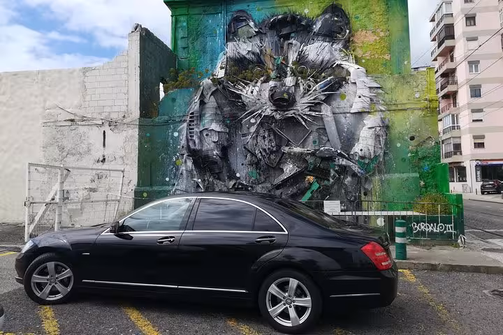 Executive car for Lisbon airport shuttle transfer parked by Lisbon street art mural, private city center drop-off