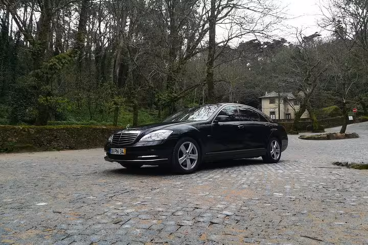 Executive sedan for Lisbon airport transfer on cobblestone road, comfortable shuttle to Lisbon city center