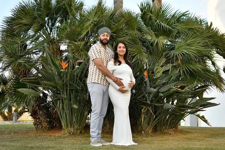 Expectant couple posing in Ammoudara garden, showcasing maternity joy and serenity during a private photoshoot.