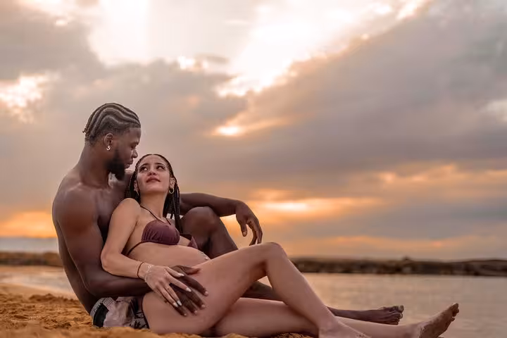 Expecting couple embraces lovingly at sunset on Ammoudara beach, perfect for a private photoshoot.
