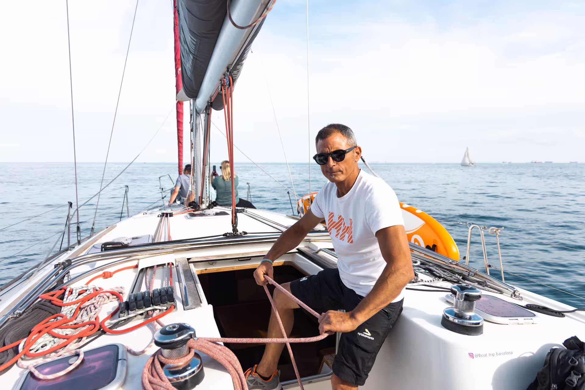 Experienced captain steering a sailboat during a private 4-hour Barcelona sailing tour with calm seas and clear skies.