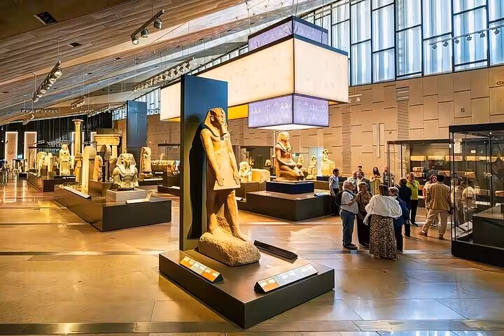 Grand Egyptian Museum gallery with ancient statues and visitors on expert female Egyptologist tour