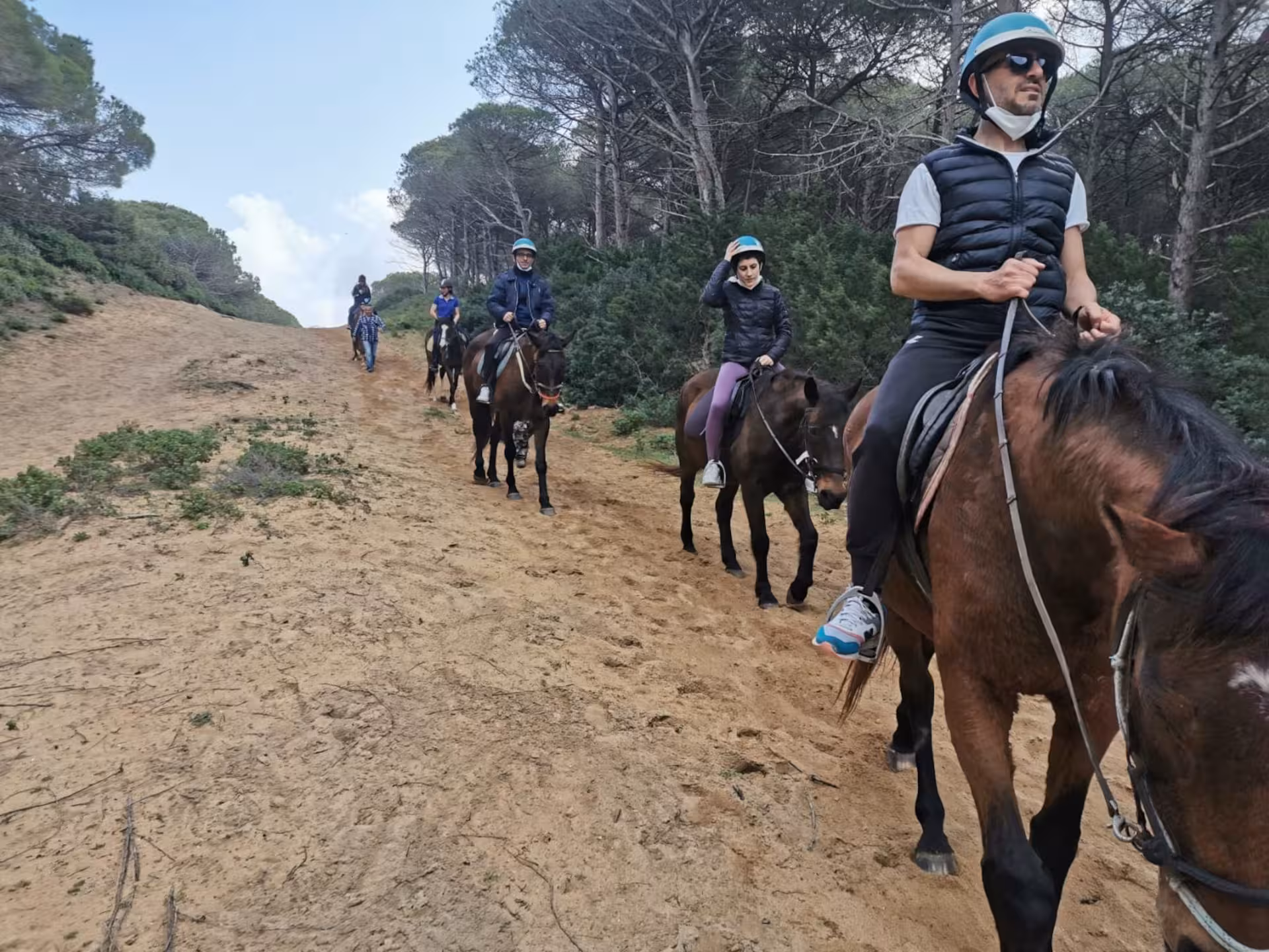 Group of experienced riders navigating sandy trails amidst forested landscapes in Porto Ferro, Alghero.