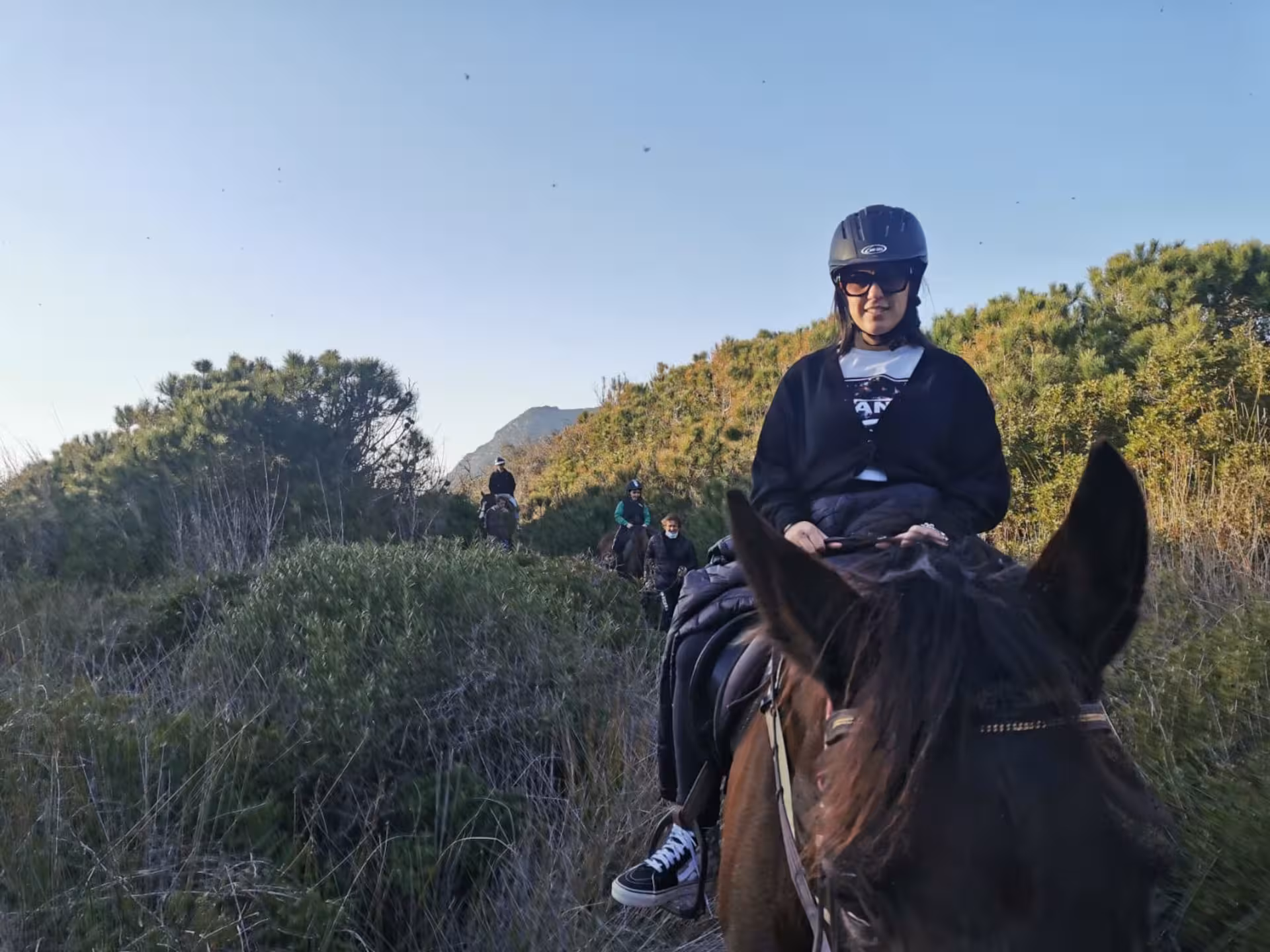 Expert rider on horseback exploring lush trails in Porto Ferro, Alghero for an adventurous equestrian experience.