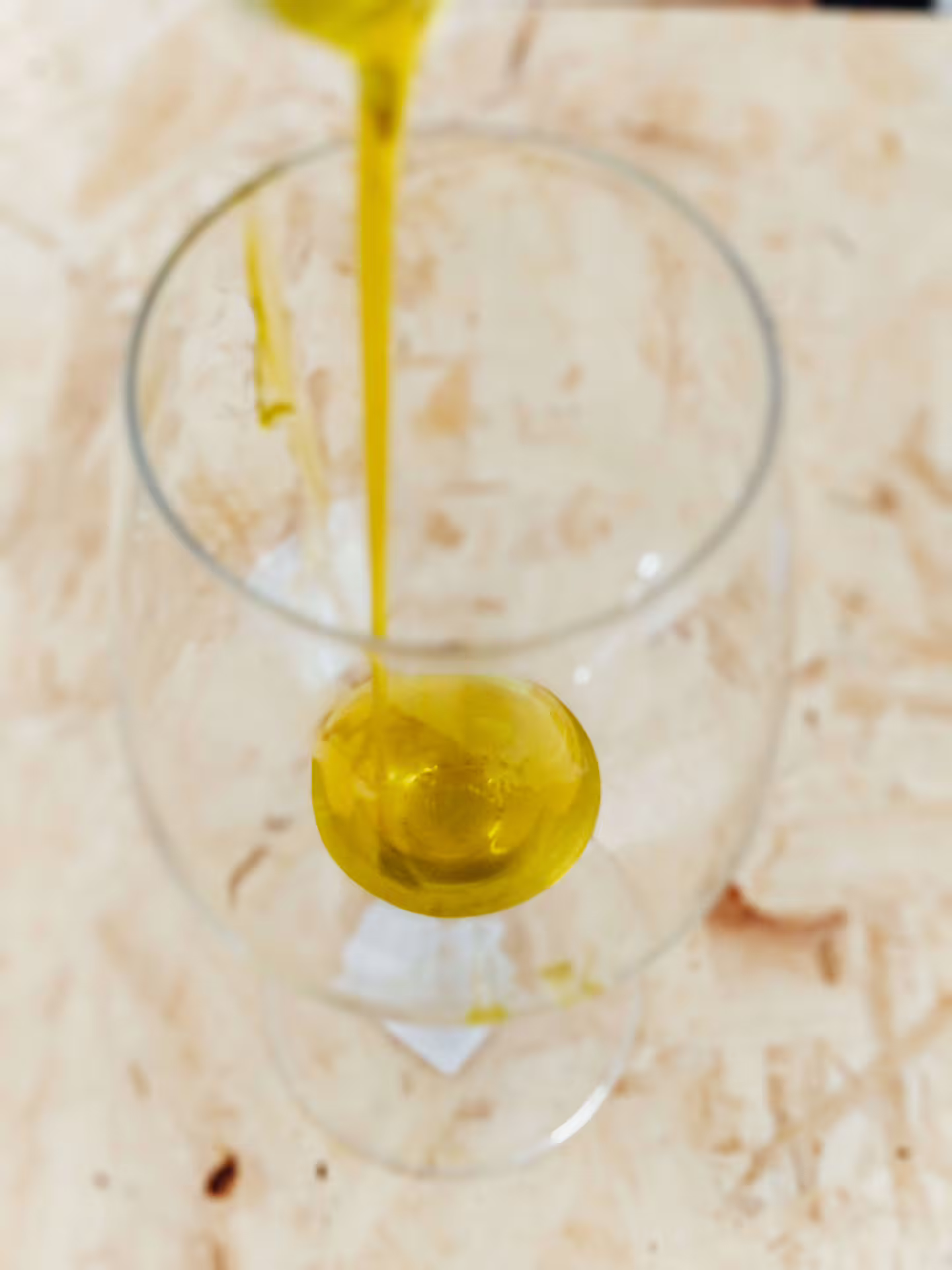 Primo piano di olio EVO appena versato nel bicchiere per tasting dopo la raccolta delle olive e visita al frantoio
