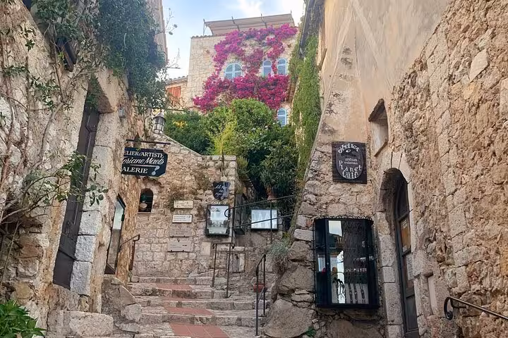 Charming stone alley in Eze adorned with vibrant bougainvillea, showcasing rustic charm on a luxury day tour.