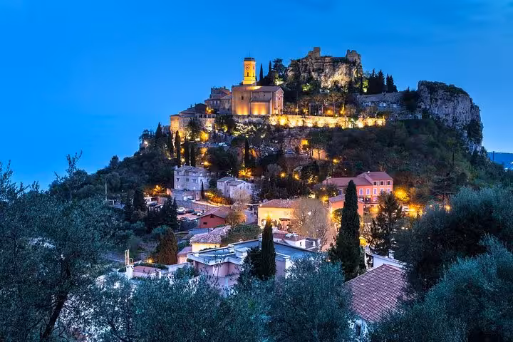 Scenic view of Eze village illuminated at dusk, showcasing medieval architecture on a hilltop near Monaco.