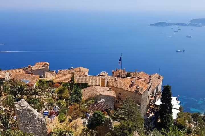 Charming Eze village with terracotta roofs and lush gardens overlooking the azure Mediterranean Sea, ideal for luxury tours.