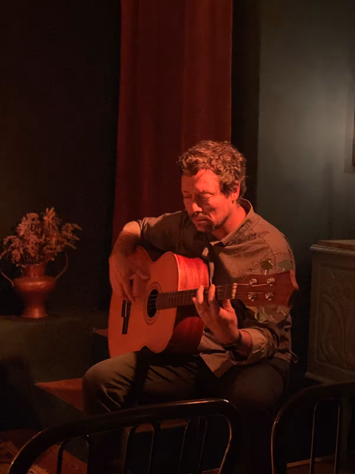 Solo guitarist performing soulful Fado music in a warmly-lit, intimate setting.