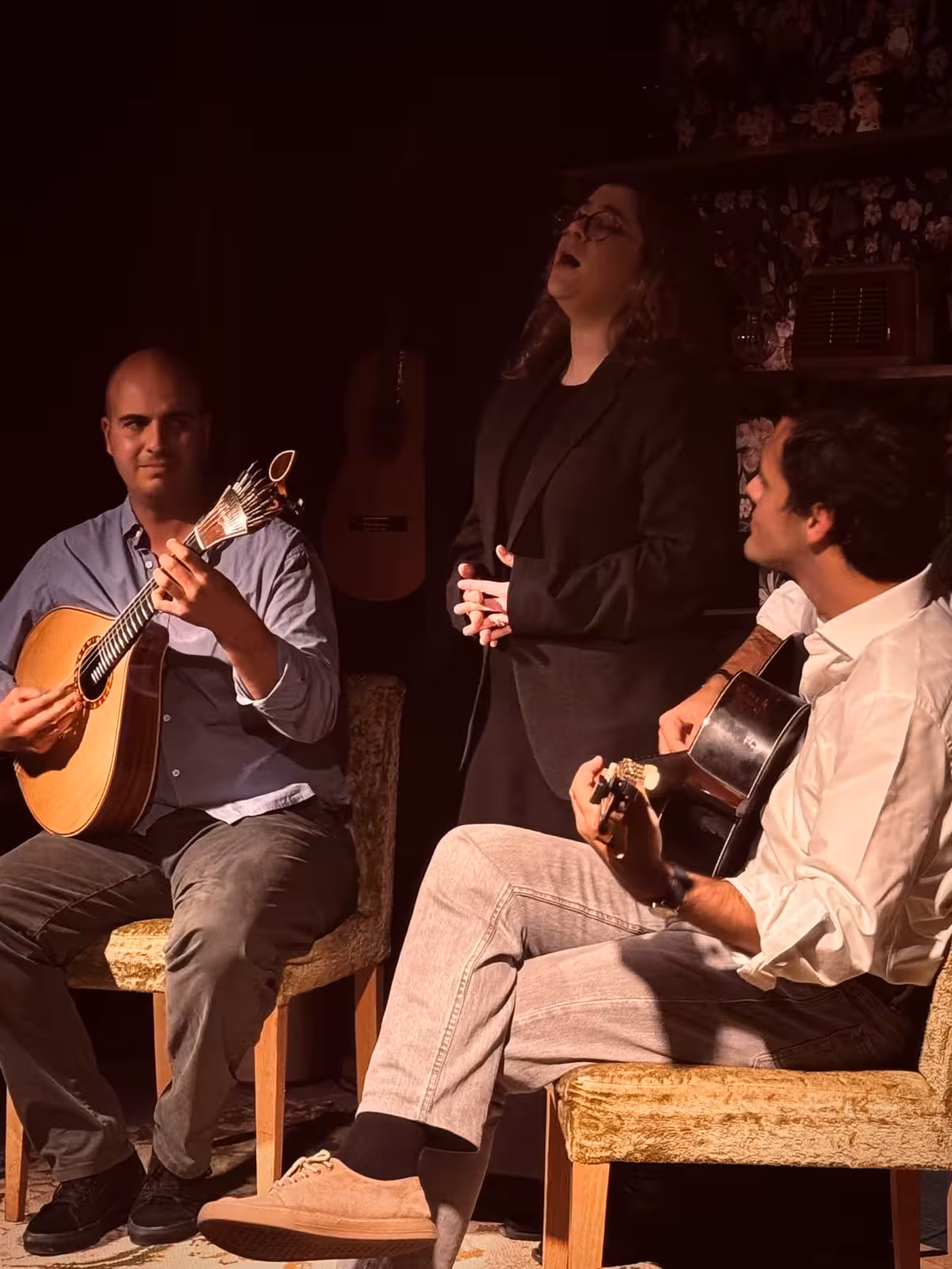 Fado singer passionately performing with two guitarists in an atmospheric, cozy venue.