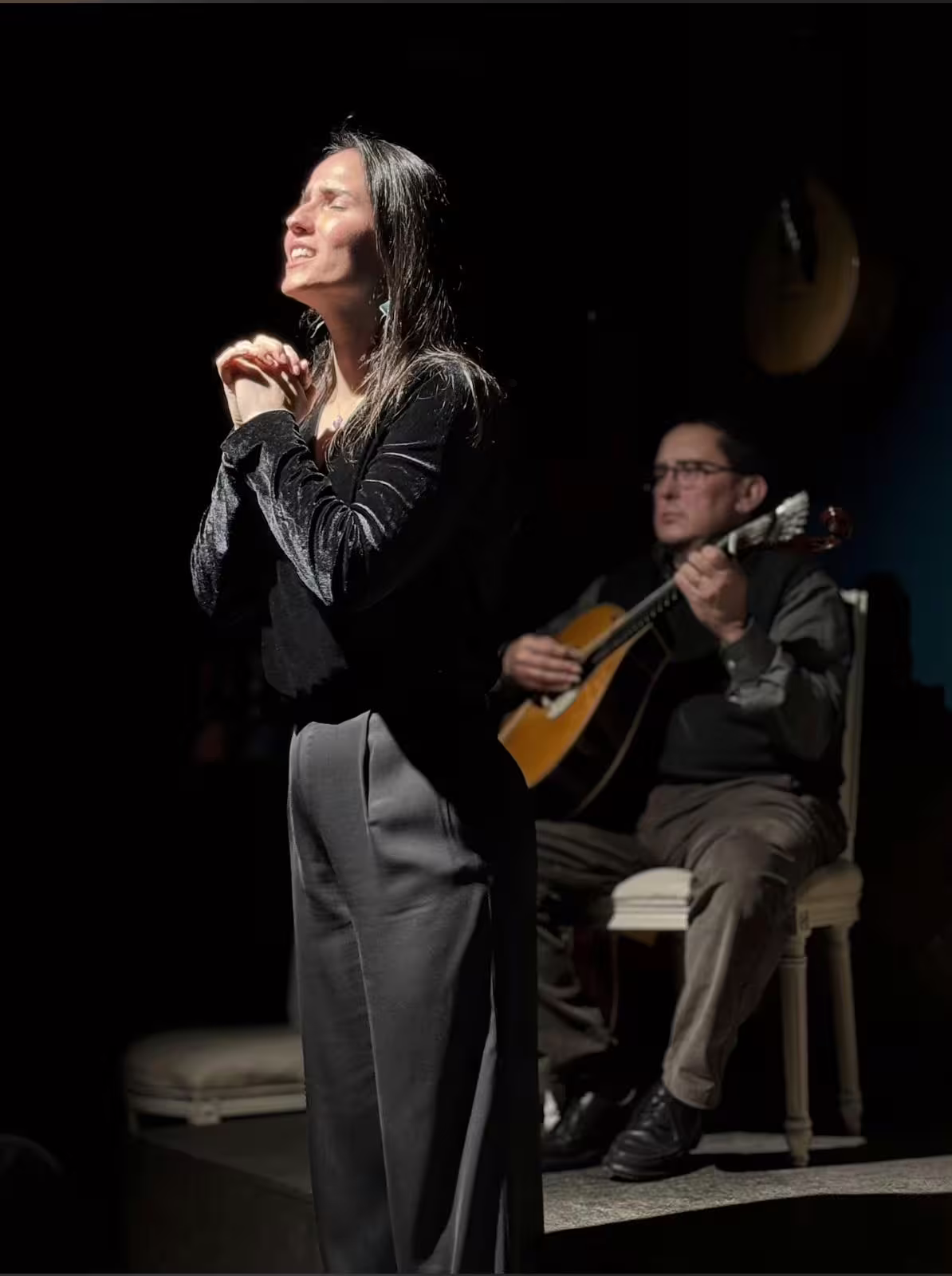 Fado singer passionately performing with a guitarist during an intimate Porto walking tour experience in a cozy setting.
