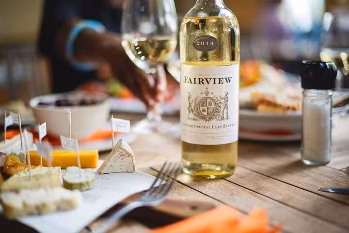A bottle of Fairview white wine with cheese samples, highlighting a wine and cheese pairing tour in Cape Town.