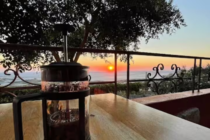 Peaceful sunrise view from a terrace with a coffee press, overlooking the serene Falasarna Beach landscape.