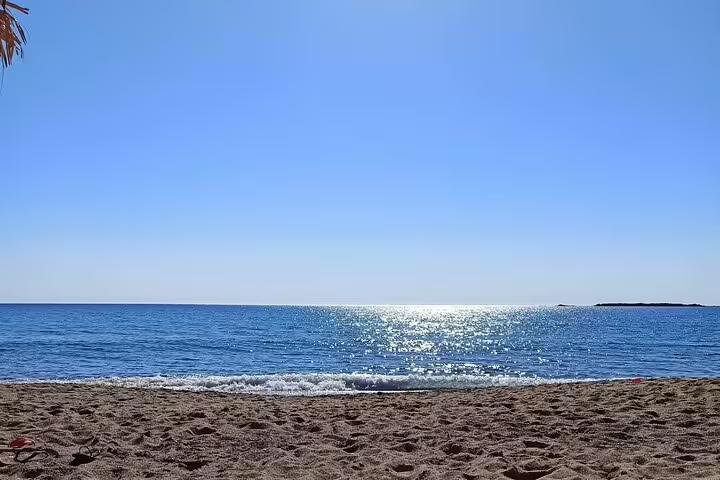 Pristine Falassarna beach with golden sand and sparkling azure waters under a clear blue sky in Chania, Crete.
