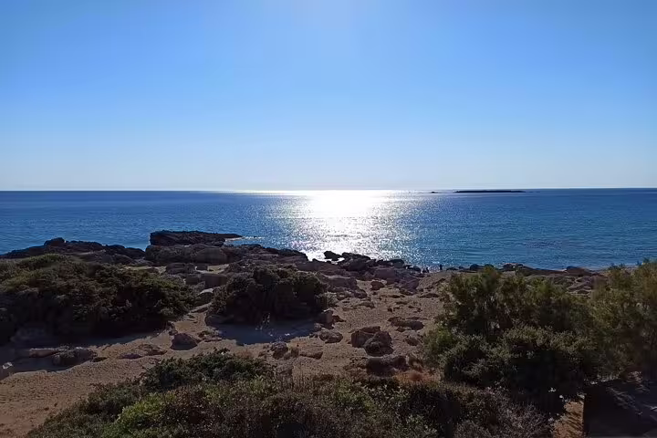 Experience the serene beauty of Falassarna Beach with the sun glistening over the calm Mediterranean Sea from Chania.