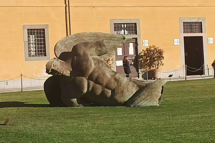 Modern fallen angel sculpture on the green lawn of Piazza dei Miracoli in Pisa, a cultural stop on the La Spezia private tour