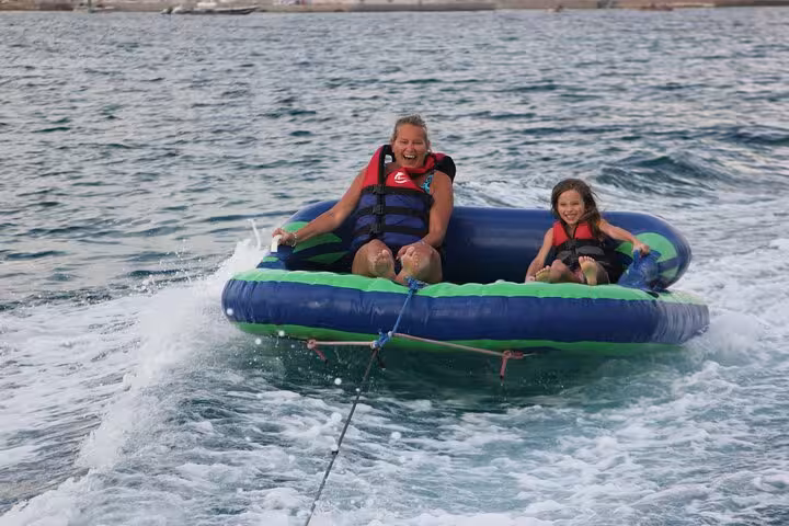 Family enjoying a banana boat ride on the Hurghada Hula Hula Island sea trip, Red Sea water sports fun