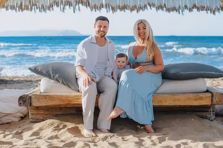 Family sitting on a beach lounger during a private Heraklion photoshoot, with the ocean waves gently crashing behind them.