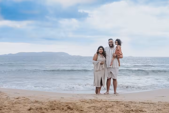 Family enjoying a beach photoshoot in Gouves with a scenic ocean backdrop and clear skies.