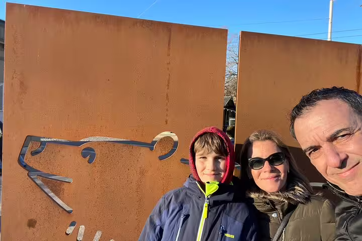 Family posing by a bear outline sculpture in Bern, Switzerland, during a self-guided scavenger hunt sightseeing tour