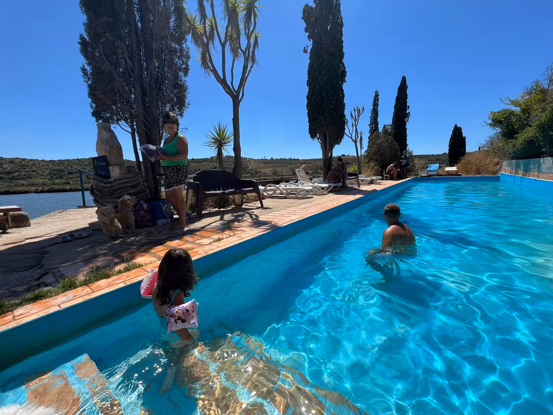 Family relaxing by a riverside infinity pool with sun loungers and views of the Algarve countryside on a private boat charter stop