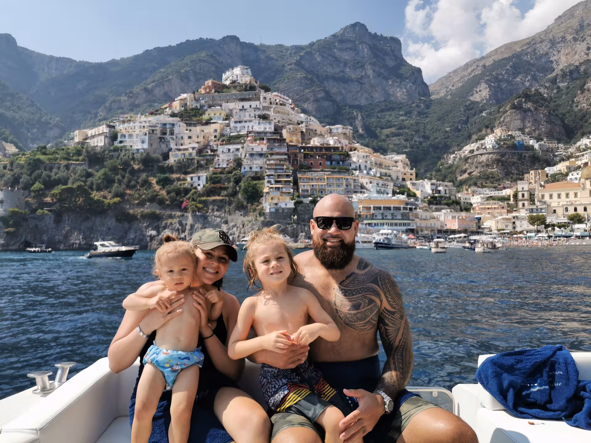 Family enjoying a scenic boat tour with picturesque Positano in the background from Sorrento.