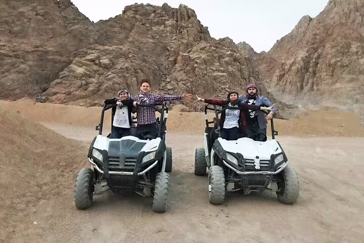 Families posing with off-road buggies in Sinai canyon, Sharm El Sheikh desert safari tour photo stop