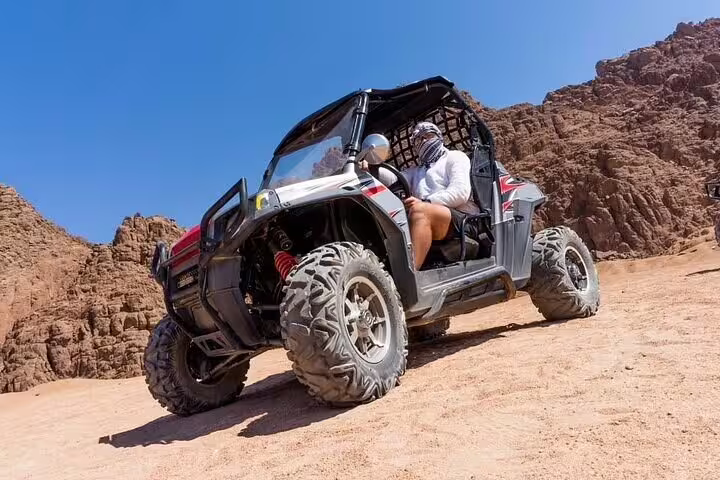 Off-road buggy climbing rocky Sinai canyon on family desert safari from Sharm El Sheikh with guided adventure ride