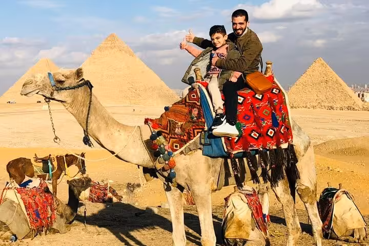 Family camel ride at the Giza Pyramids, Cairo, on a private tour with lunch and desert photo stop