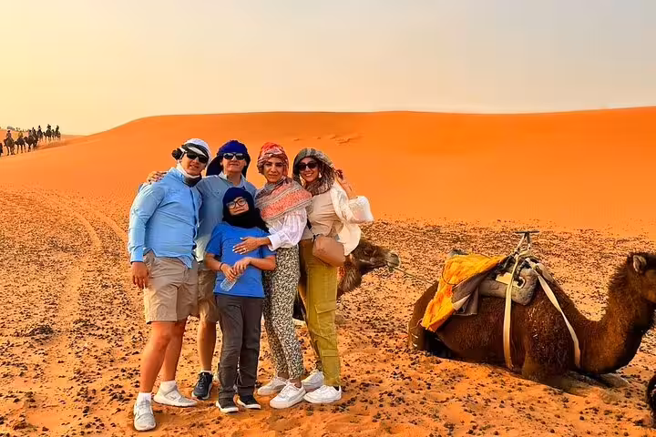 Family photo with camel in Merzouga Sahara dunes, camel trek stop on 3-day private desert tour from Marrakech
