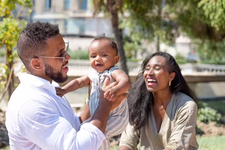 Family candid with baby during a private Monaco travel photographer tour in a sunny garden setting