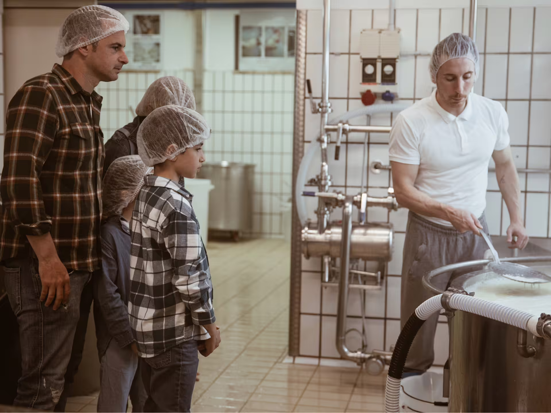 Family observes cheesemaker stirring milk in a traditional cheese factory in Isernia countryside.